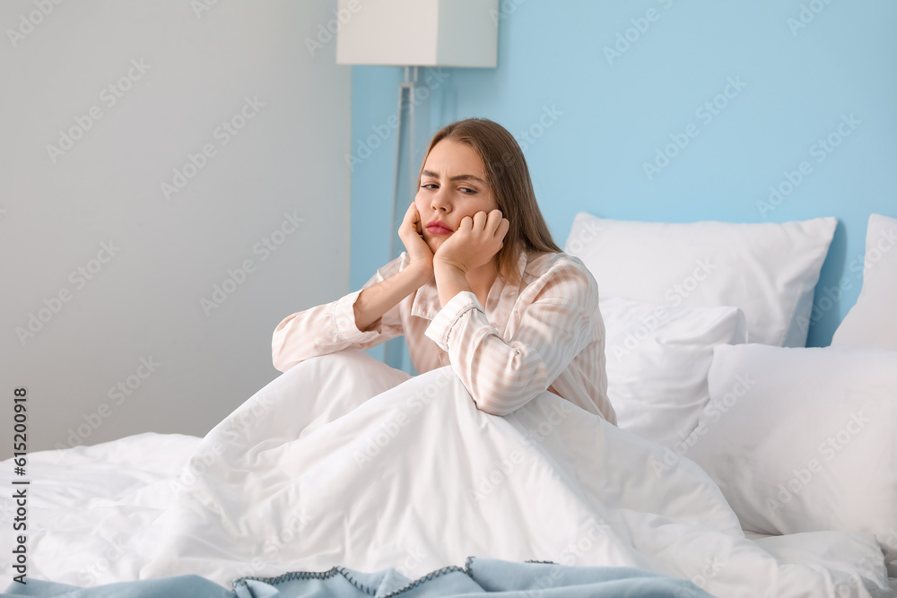 Upset young woman sitting on bed at home in morning Upset young woman sitting on bed at home in morning