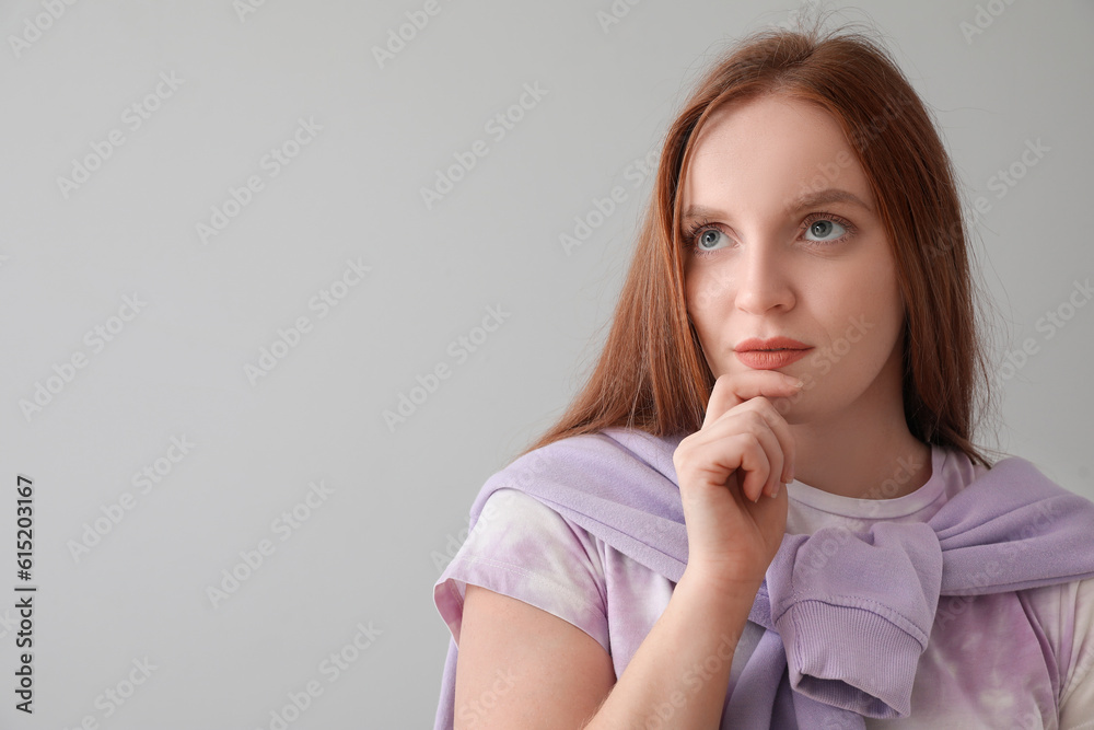 Thoughtful young redhead woman on grey background, closeup Thoughtful young redhead woman on grey background, closeup