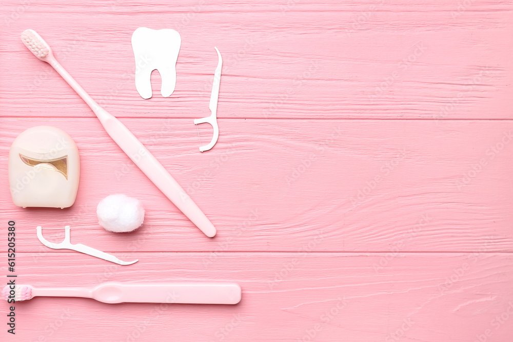 Composition with dental floss, toothpicks and brushes on pink wooden background Composition with dental floss, toothpicks and brushes on pink wooden background