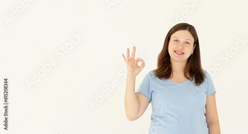 Young beautiful pregnant woman wearing t-shirt over isolated white background smiling positive doing ok sign with hand and fingers. Successful expression.