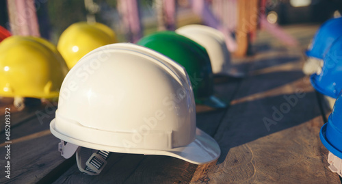 Safety helmet (hard hat) for engineer, safety officer, or architect, place on wooden floor. Yellow, White, green, blue, and orange safety hat (helmet) on construction site-banner image.