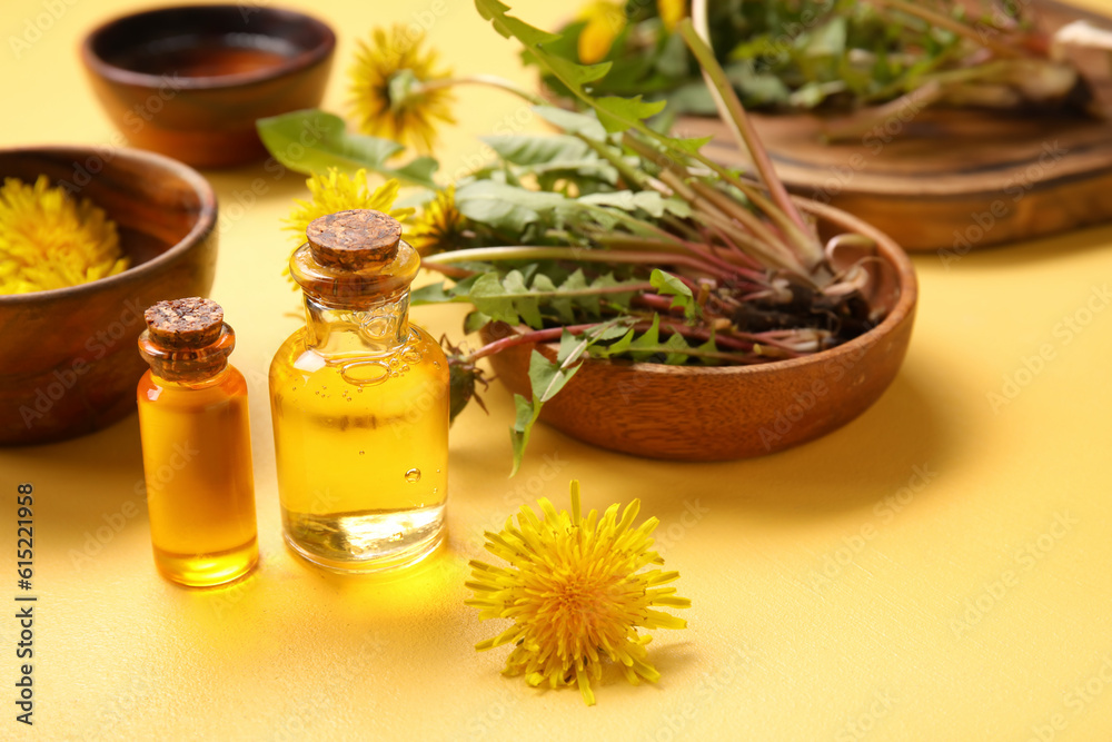 Bottles with cosmetic oil and bowls of dandelion flowers on yellow background Bottles with cosmetic oil and bowls of dandelion flowers on yellow background