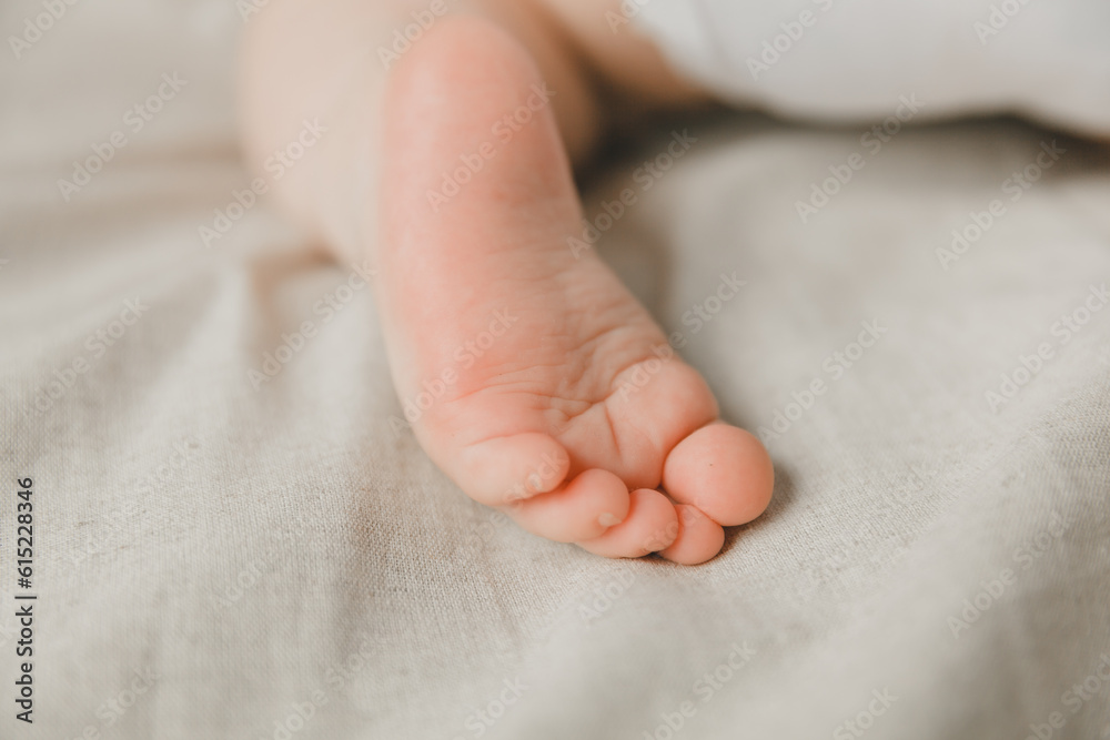 mom's hands hold the baby's legs in on a cotton bed, hygiene and care and care for the newborn.toddler's heel mom's hands hold the baby's legs in on a cotton bed, hygiene and care and care for the newborn.toddler's heel