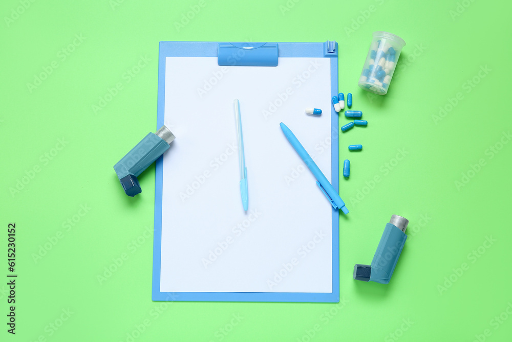 Composition with asthma inhalers, clipboard and box of pills on green background Composition with asthma inhalers, clipboard and box of pills on green background