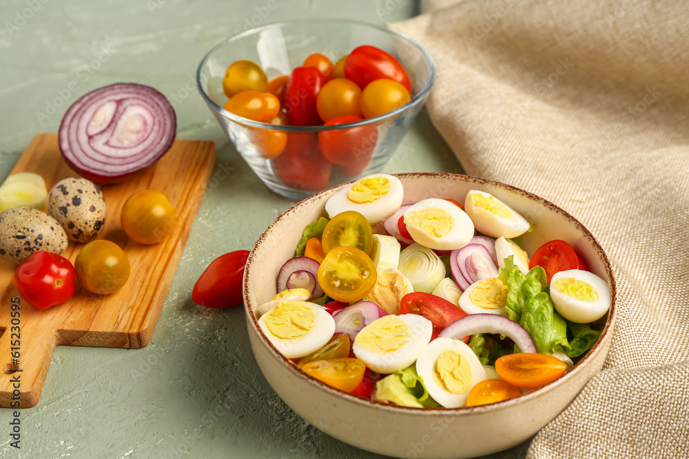 Tasty salad with quail eggs, tomatoes, onion and lettuce on color background, closeup