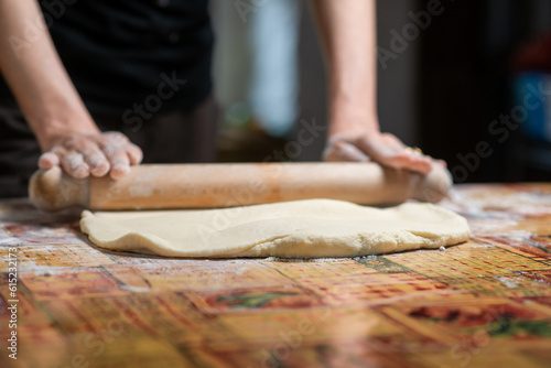 Woman rolls out dough with rolling pin. Preparation of dough for dumplings, dumplings, pie.