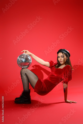 Fototapeta Naklejka Na Ścianę i Meble -  Fashionable beautiful woman with disco ball posing on red background