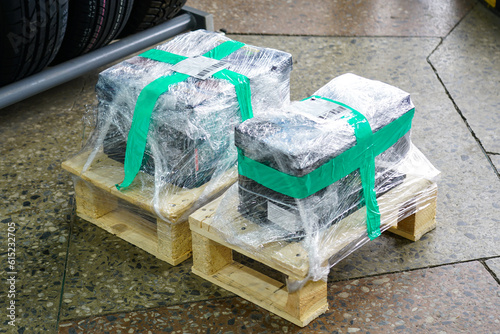 New car battery wrapped in film on a small wooden pallet, delivery of goods to auto parts store photo