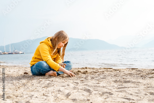 Lonely beautiful sad girl teenager sits thoughtfully on sand sea beach. Dreams,anxiety,worries about future,school friends, parents. Teen bullying, psychological problems in adolescent puberty period © velirina