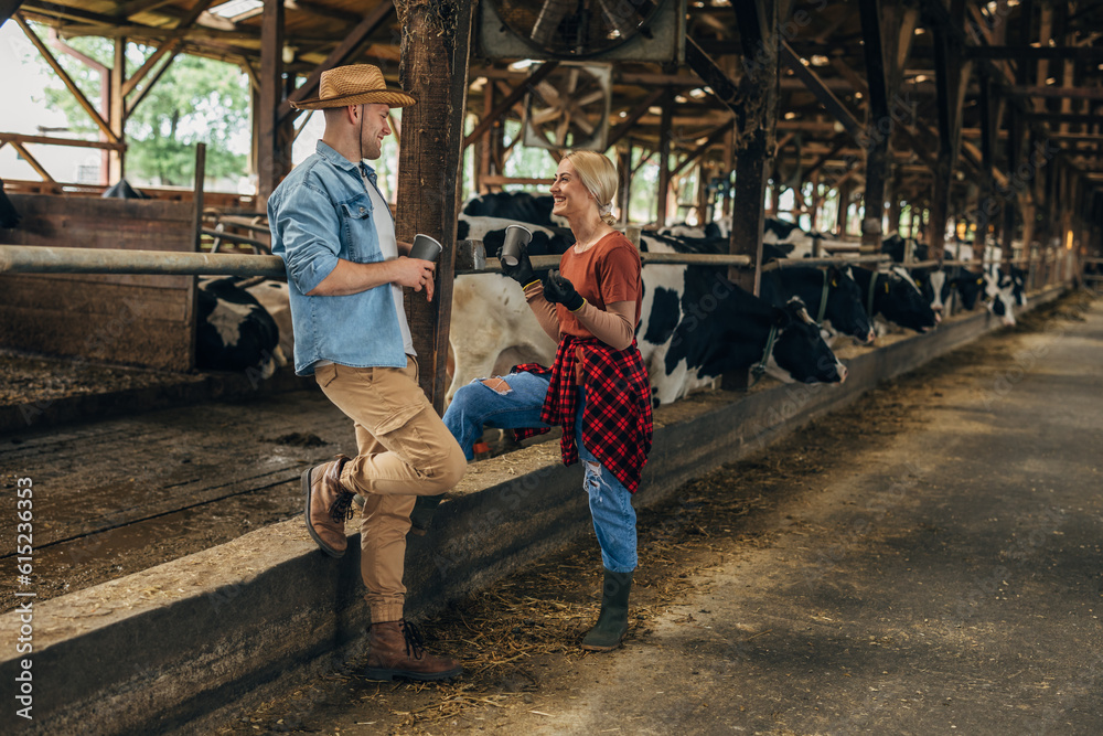 Two young adults standing in a stable, drinking coffee and talking. Two young adults standing in a stable, drinking coffee and talking.