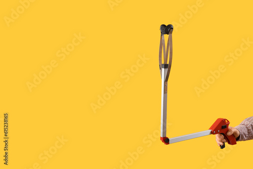Female hand holding long reach grabber tool on yellow background