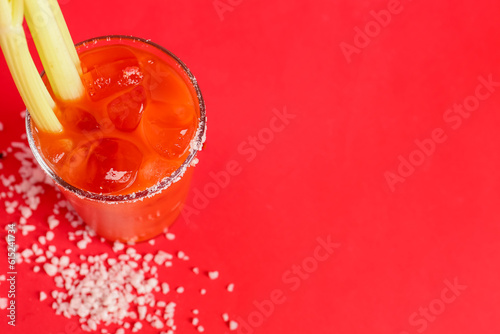 Glass of bloody mary with celery and salt on red background © Pixel-Shot