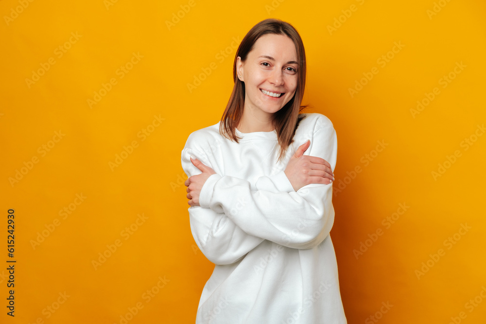 Friendly smiling young woman embraces herself because she empowers women. Friendly smiling young woman embraces herself because she empowers women.