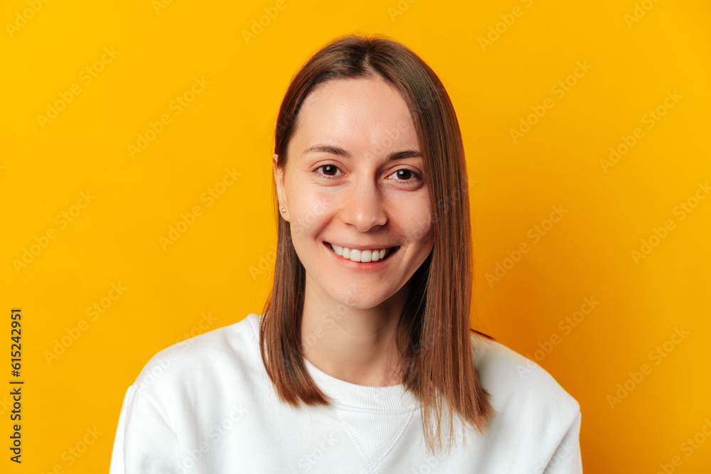 Close up studio portrait of a wide smiling woman over yellow backdrop. Close up studio portrait of a wide smiling woman over yellow backdrop.