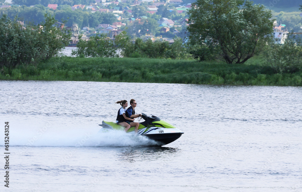 On a jet ski together, at high speed on the Volga River. A sunny summer day. Sports and recreation.