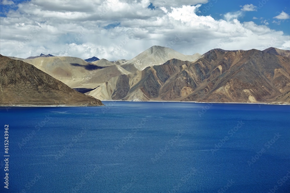 A serene and tranquil scene unfolds as sunlight dances upon the calm waters of Pangong Lake in Ladakh, India.