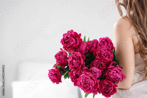 Fototapeta Naklejka Na Ścianę i Meble -  Young woman with bouquet of peony flowers in bedroom