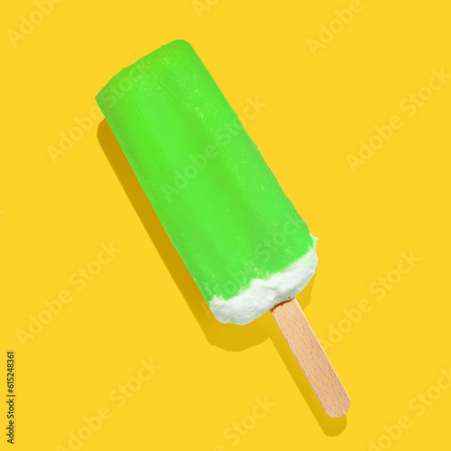 Green ice cream on a stick on yellow pastel background