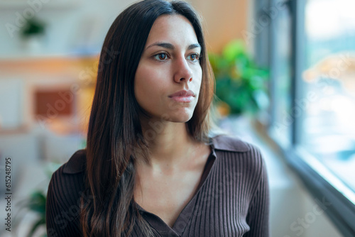 ..Beautiful young woman looking forwards while standing in the living room at home