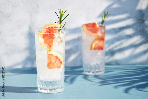 Summer chilled grapefruit cocktail with ice and rosemary sprig. Summer cold drinks. Soda with citrus