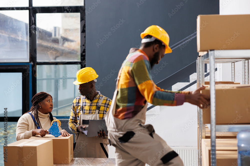 Warehouse workers packing customer order package with adhesive dispenser. Storehouse man and woman employees using sticky tape for cardboard box closing and discussing order pick ticket Warehouse workers packing customer order package with adhesive dispenser. Storehouse man and woman employees using sticky tape for cardboard box closing and discussing order pick ticket