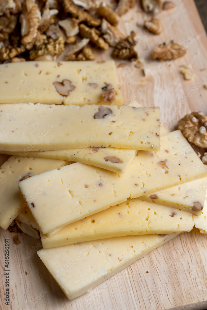 Sliced piece of milk cheese with walnuts