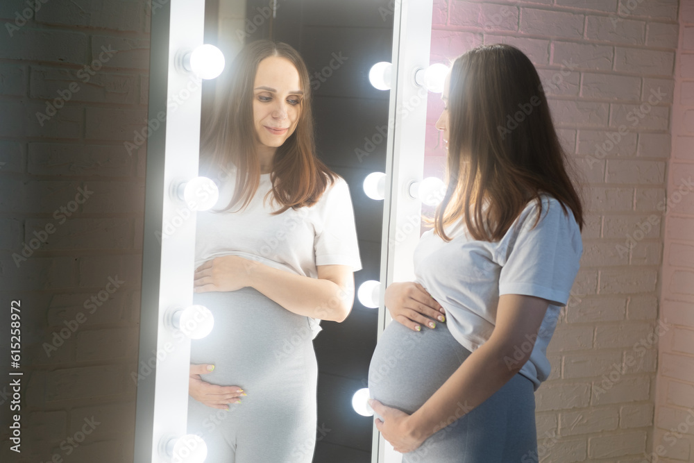 Pregnant woman with big belly in front of mirror, standing in room. Pregnant woman with big belly in front of mirror, standing in room.