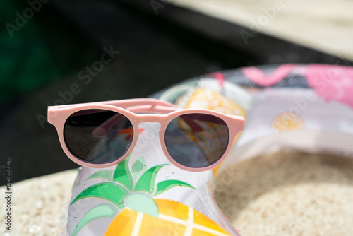 Summertime vacation, day at the swimming pool and summer fun concept with view of sunglasses and inflatable ring pool float 