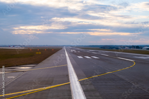 In the airport setting, a lengthy and unobstructed runway reaches out into the distance, adorned with prominent aircraft markings and unmistakable pathways designed for seamless takeoffs and landings.