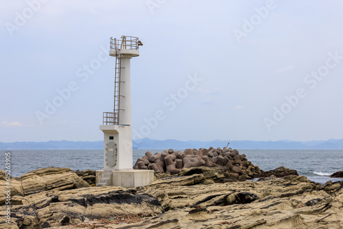 漁港の入口の岩場に設置された白い灯台
