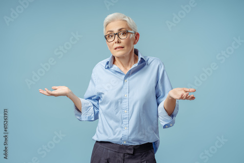 Puzzled clueless senior woman shrugging shoulders with hesitation
