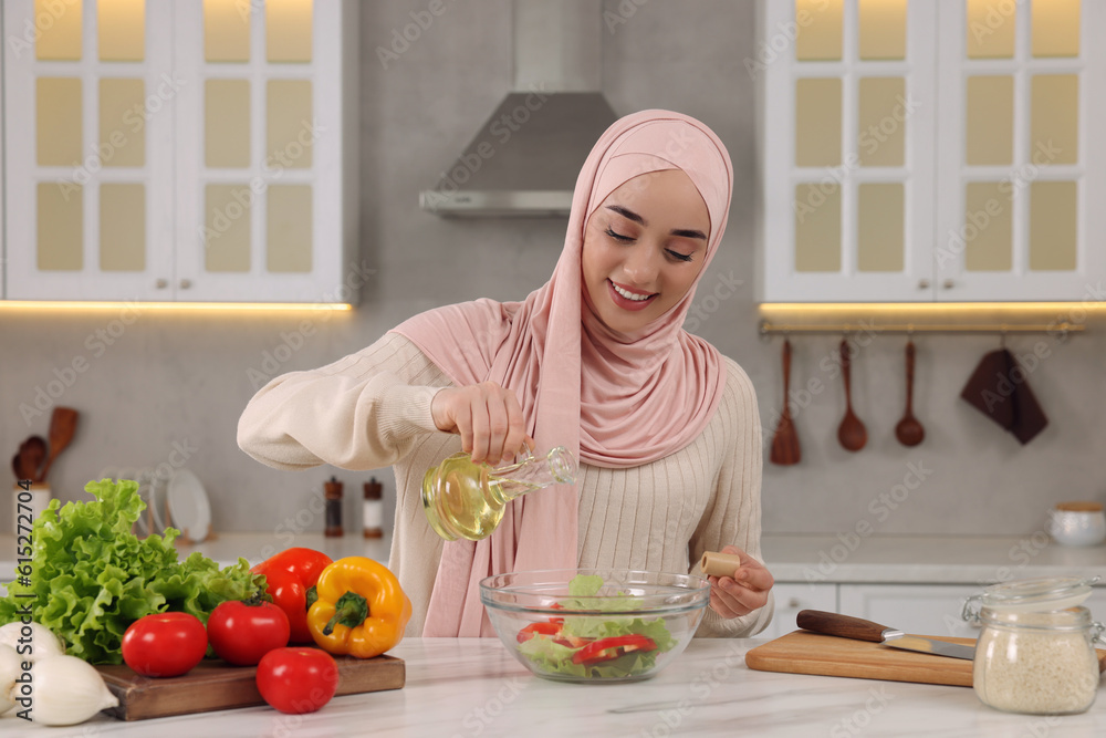 Muslim woman making delicious salad with vegetables at white table in kitchen Muslim woman making delicious salad with vegetables at white table in kitchen