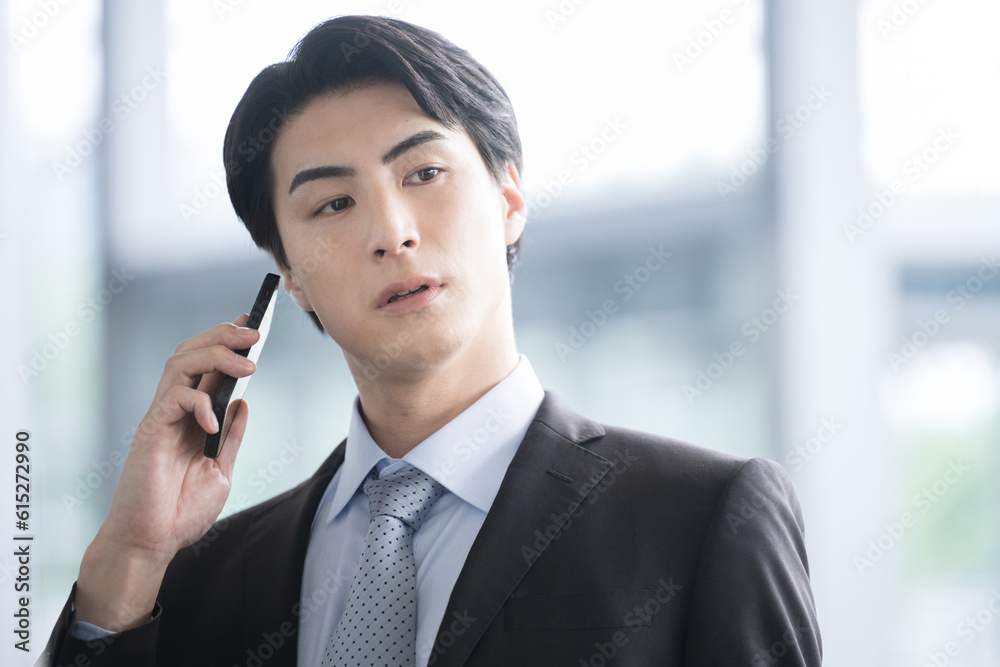 スマホを持って電話連絡をしようとするハンサムな男性 何か思い出すイメージ スマホを持って電話連絡をしようとするハンサムな男性 何か思い出すイメージ