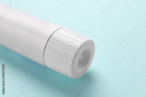 Tube of ointment on light blue background, closeup. Space for text