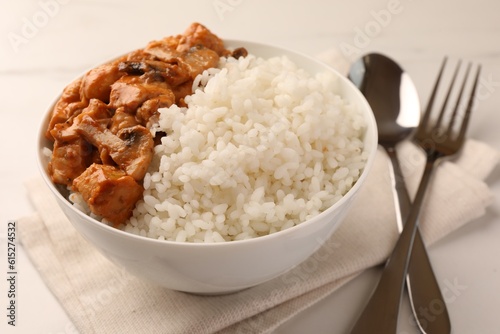 Bowl of delicious rice with meat and mushrooms on white table, closeup