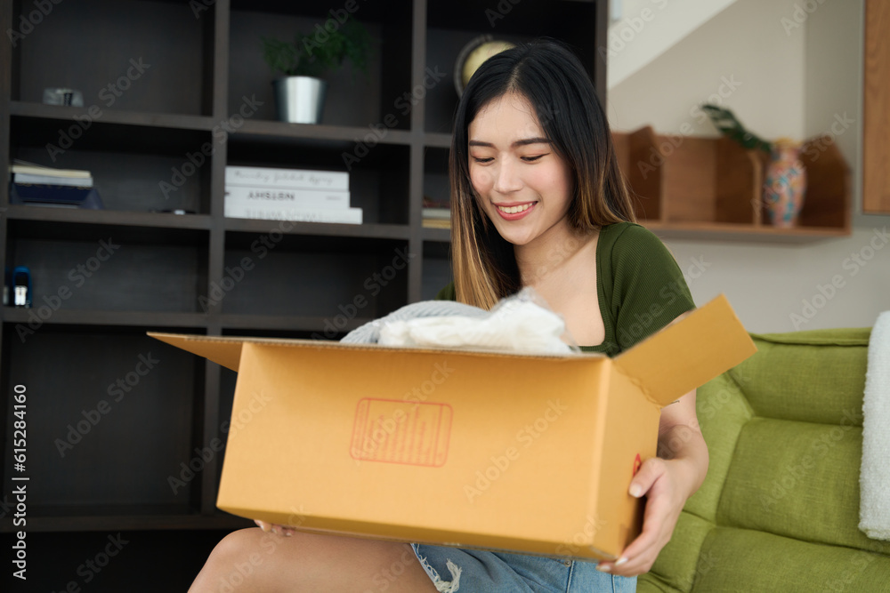 Young asian women unpacking awaited parce looking inside, sitting at sofa, unhappy customer opening cardboard box with online store order,Delivery service concept. Young asian women unpacking awaited parce looking inside, sitting at sofa, unhappy customer opening cardboard box with online store order,Delivery service concept.