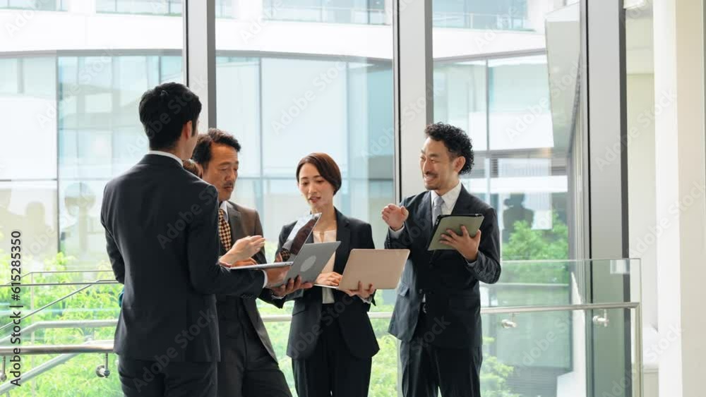 Group of Asian businesspeople meeting in lobby with laptops and tablets. Digital transformation. Smart office. Group of Asian businesspeople meeting in lobby with laptops and tablets. Digital transformation. Smart office.