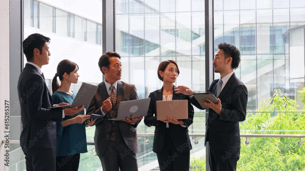 Group of Asian businesspeople meeting in lobby with laptops and tablets. Digital transformation. Smart office. Group of Asian businesspeople meeting in lobby with laptops and tablets. Digital transformation. Smart office.