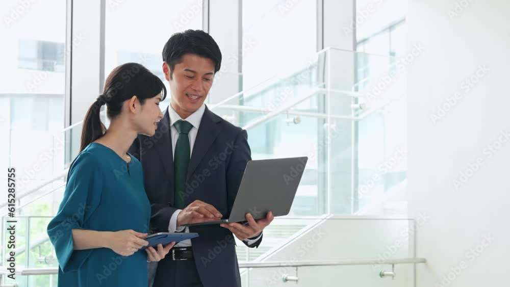 Group of Asian businesspeople meeting in lobby with laptops and tablets. Digital transformation. Smart office.