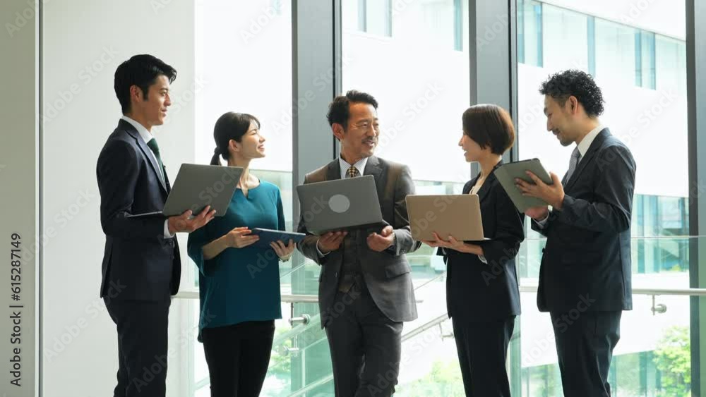 Group of Asian businesspeople meeting in lobby with laptops and tablets. Digital transformation. Smart office. Group of Asian businesspeople meeting in lobby with laptops and tablets. Digital transformation. Smart office.