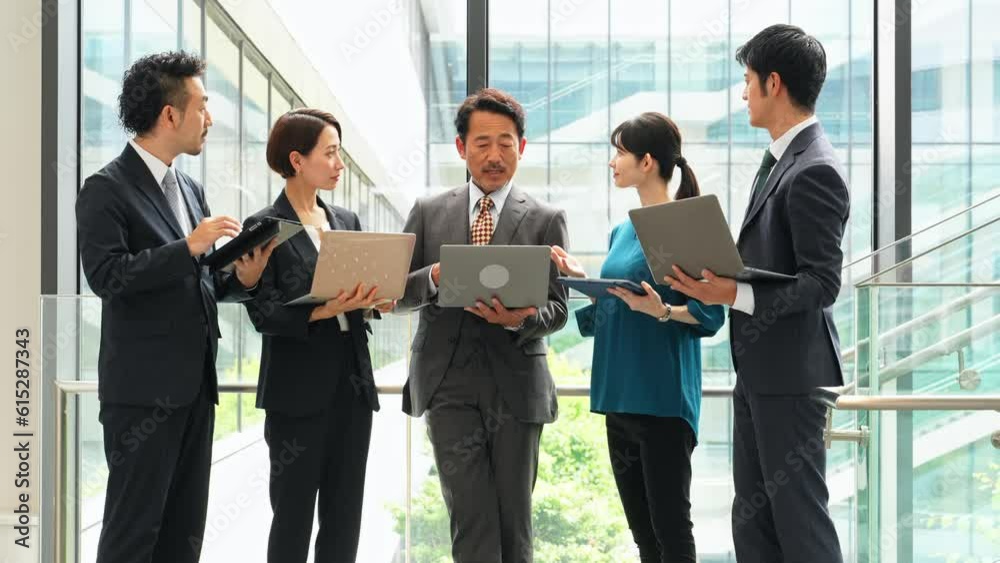 Group of Asian businesspeople meeting in lobby with laptops and tablets. Digital transformation. Smart office. Group of Asian businesspeople meeting in lobby with laptops and tablets. Digital transformation. Smart office.