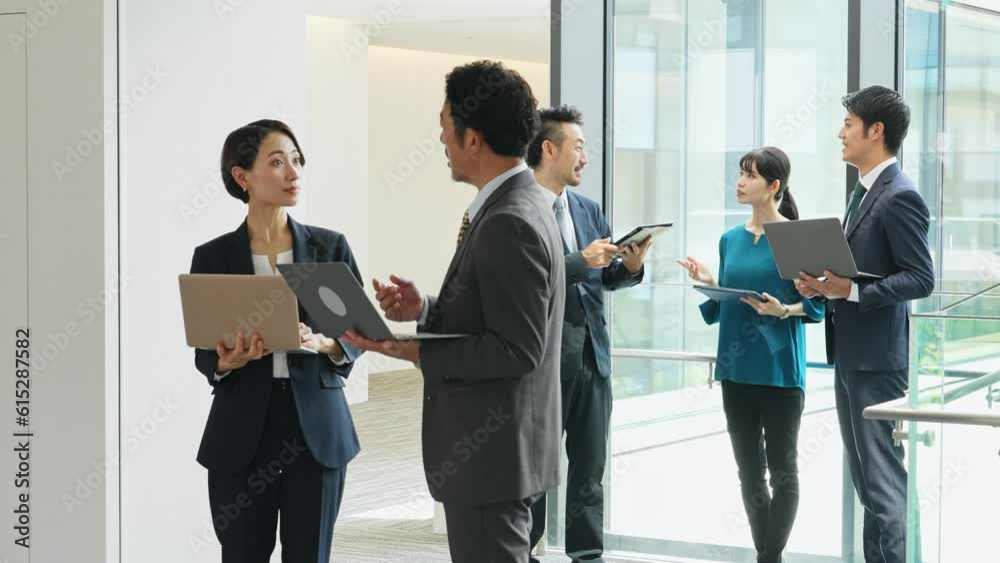 Group of Asian businesspeople meeting in lobby with laptops and tablets. Digital transformation. Smart office. Group of Asian businesspeople meeting in lobby with laptops and tablets. Digital transformation. Smart office.