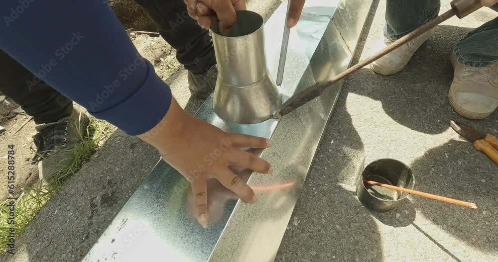 Zinc rain gutter welding by using soldering copper. Technician is