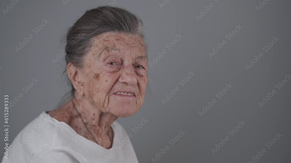 Senior woman 90 years old smiles, laughs and shows a denture on a gray background. Elderly female with deep wrinkles and gray hair happy in a good mood studio portrait looking at camera. Senior woman 90 years old smiles, laughs and shows a denture on a gray background. Elderly female with deep wrinkles and gray hair happy in a good mood studio portrait looking at camera.