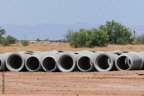 Concrete sewer round pipes laying on a vacant dirt lot 