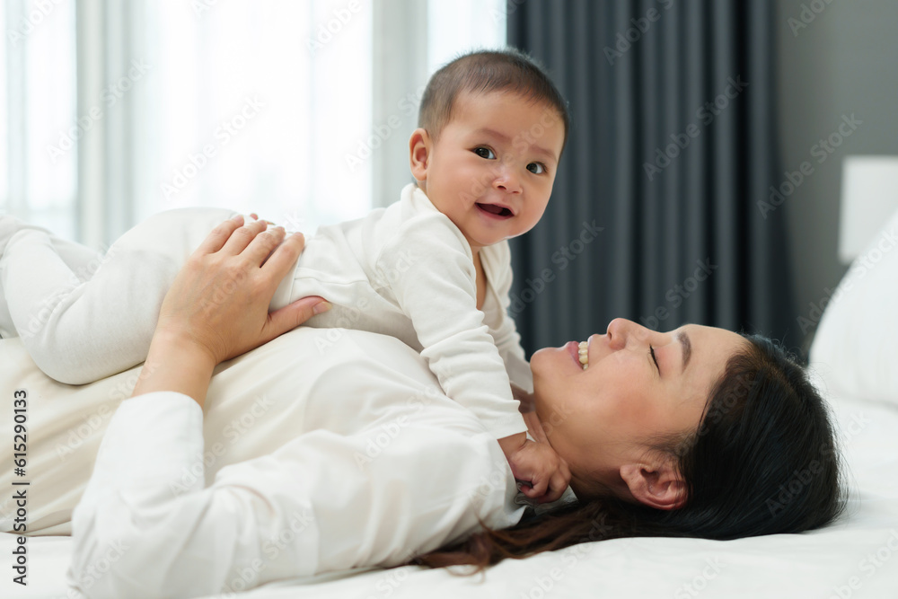 happy mother lying and playing with her infant baby on bed happy mother lying and playing with her infant baby on bed