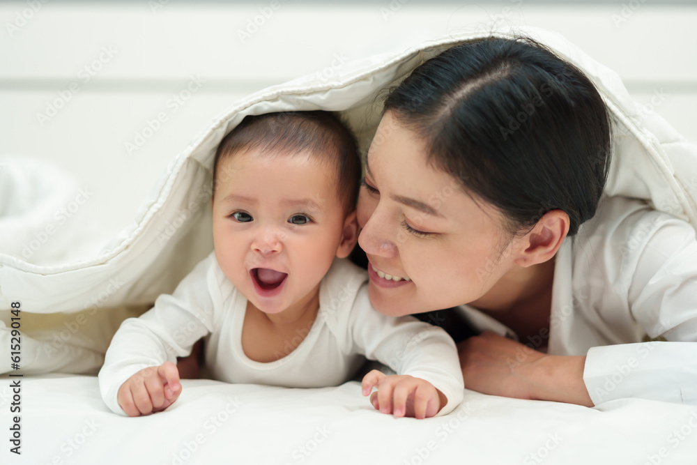happy mother and infant baby lying prone in blanket on bed happy mother and infant baby lying prone in blanket on bed
