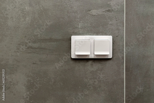 2 white electrical sockets or outlets against a gray concrete wall