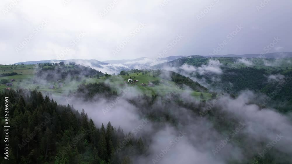 Aerial orbit view of village on top of green forest hill on a misty morning, Transylvania, Romania Aerial orbit view of village on top of green forest hill on a misty morning, Transylvania, Romania