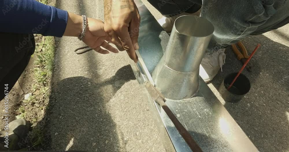 Zinc rain gutter welding by using soldering copper. Technician is